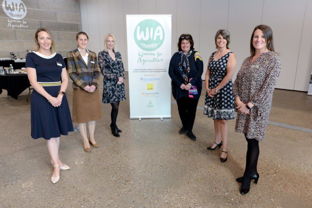 Six women standing by a white banner with Women in Agriculture (WIA)