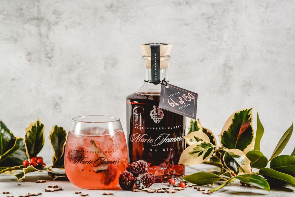 Massingberd Mundy's mulled winter berry gin bottle, labelled, with glass and assorted greenery